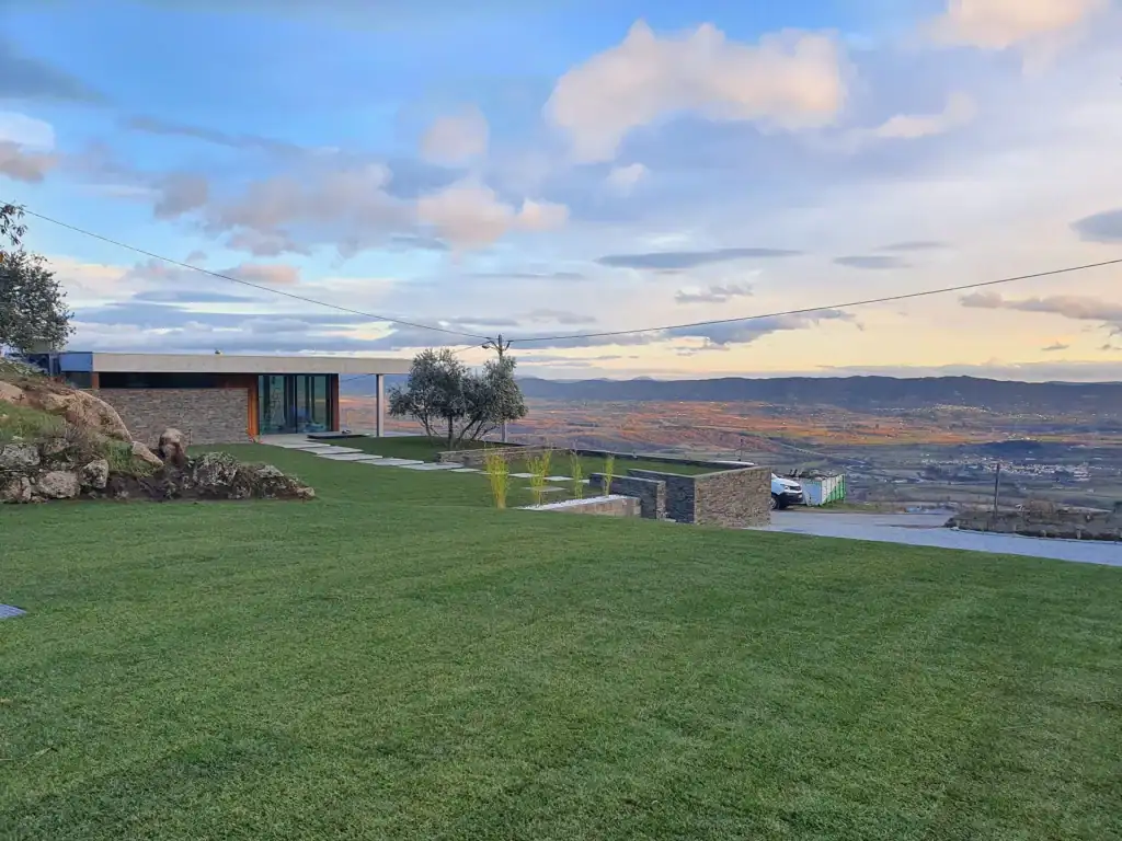 Jardim moderno com relvado e arquitectura paisagística, vista panorâmica ao pôr do sol